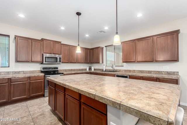 kitchen featuring sink, a center island, hanging light fixtures, light tile patterned floors, and stainless steel appliances