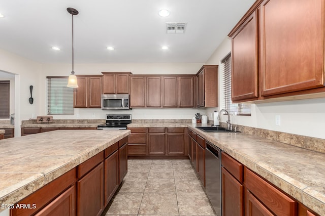 kitchen featuring stainless steel appliances, sink, light tile patterned floors, and decorative light fixtures