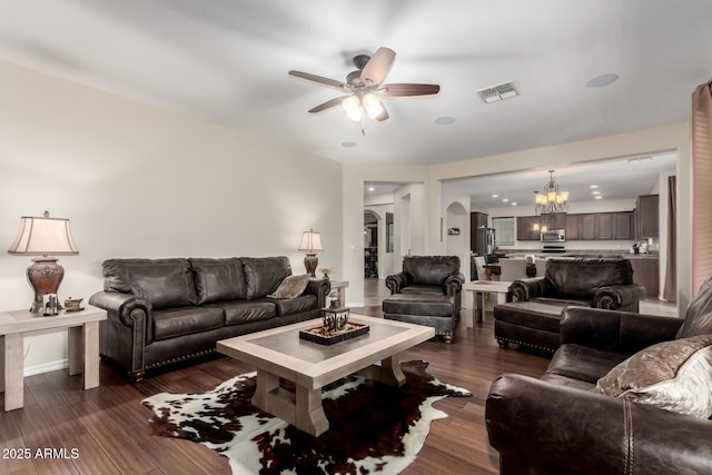 living room with ceiling fan with notable chandelier and dark hardwood / wood-style floors