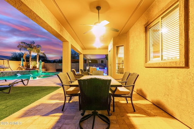 patio terrace at dusk with a fenced in pool and ceiling fan