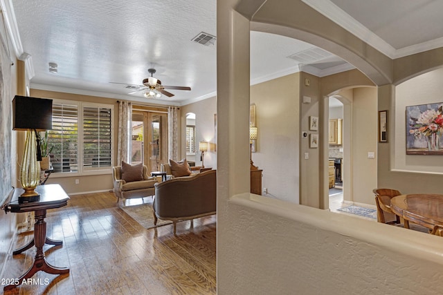 living room with hardwood / wood-style flooring, crown molding, a textured ceiling, and ceiling fan