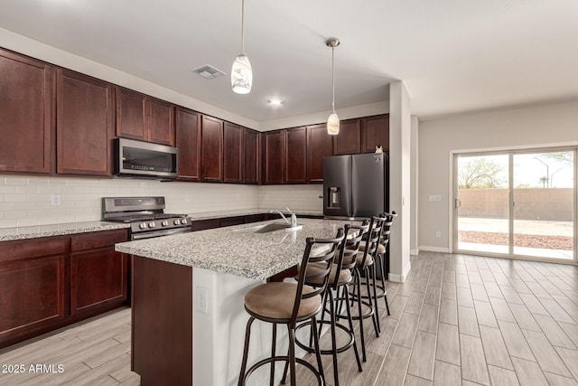 kitchen with decorative backsplash, visible vents, appliances with stainless steel finishes, and a sink