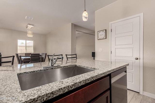 kitchen with visible vents, pendant lighting, a sink, light stone countertops, and dishwasher