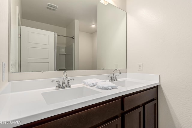 full bathroom with double vanity, visible vents, a shower, and a sink