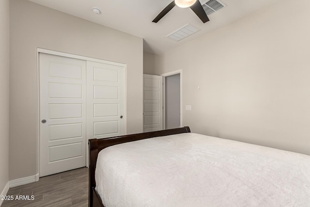 bedroom featuring a ceiling fan, wood finished floors, visible vents, and a closet