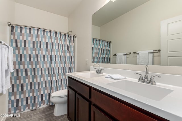 bathroom with double vanity, wood finish floors, toilet, and a sink