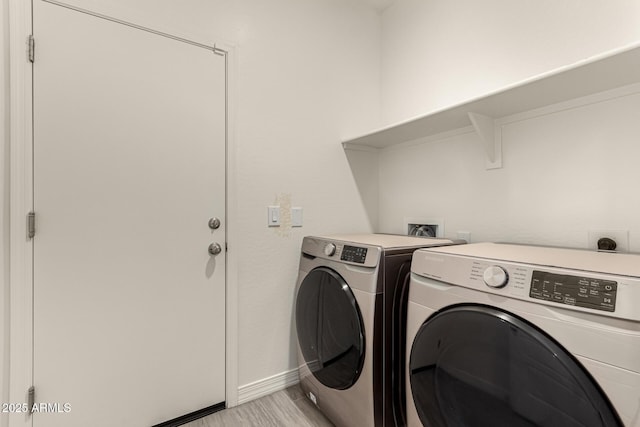 washroom featuring light wood-type flooring, baseboards, separate washer and dryer, and laundry area