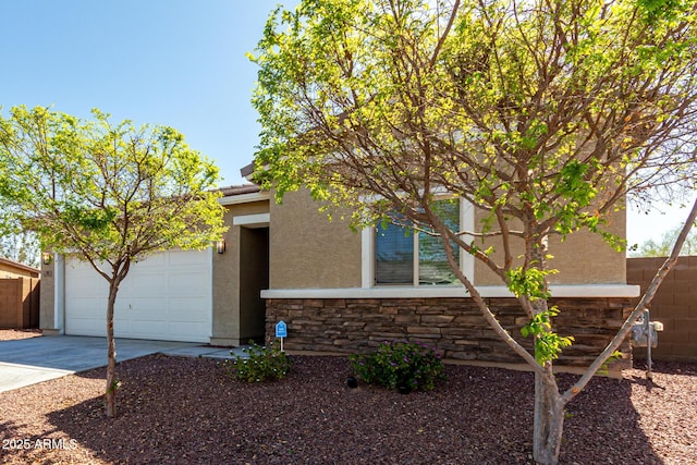 view of front facade featuring stucco siding, a garage, concrete driveway, and fence