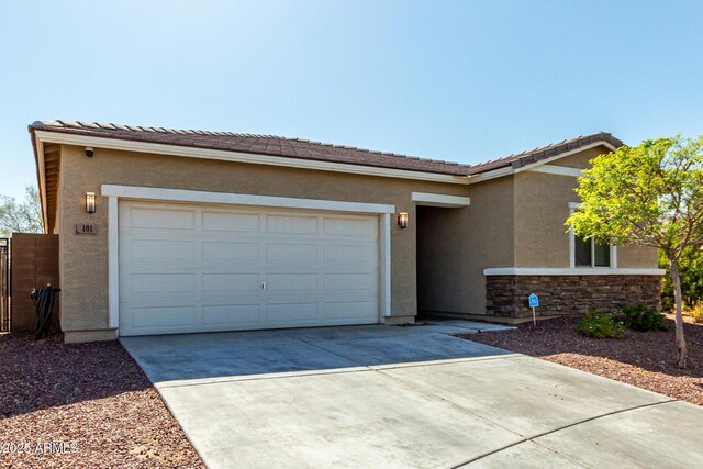 view of front facade with stone siding, stucco siding, driveway, and a garage