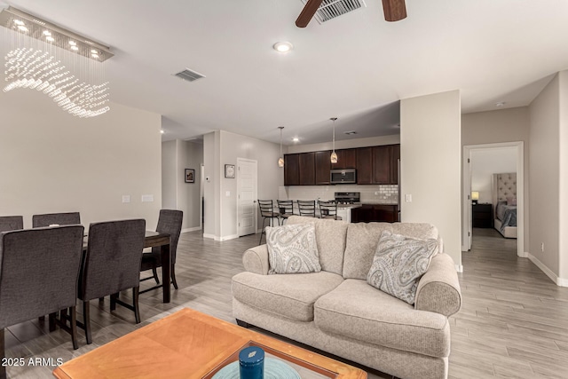 living area with a ceiling fan, light wood-style floors, and visible vents