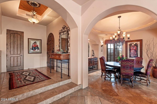 tiled dining area with a chandelier and a raised ceiling