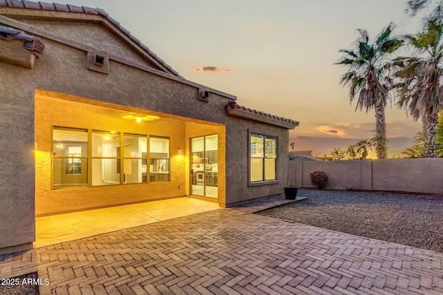 back house at dusk with a patio area