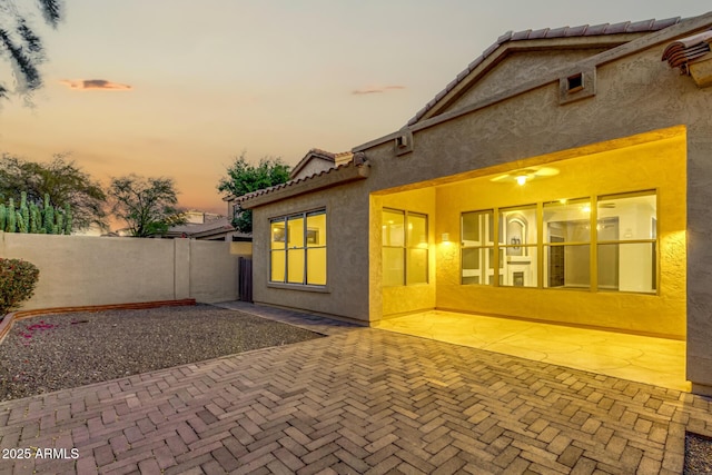 back house at dusk with a patio area