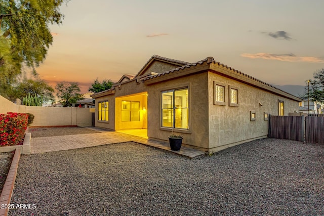 back house at dusk featuring a patio area