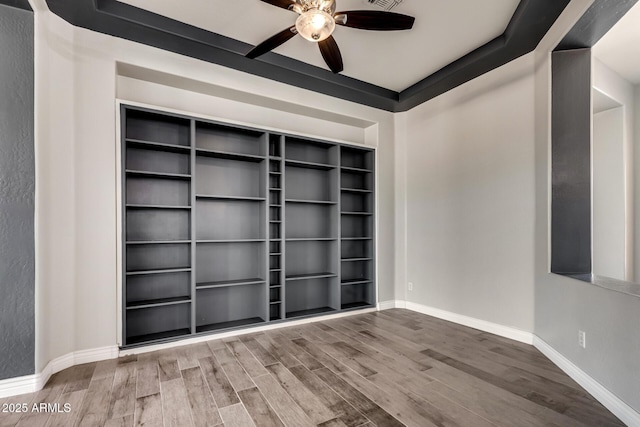 spare room featuring wood-type flooring, ceiling fan, and built in shelves