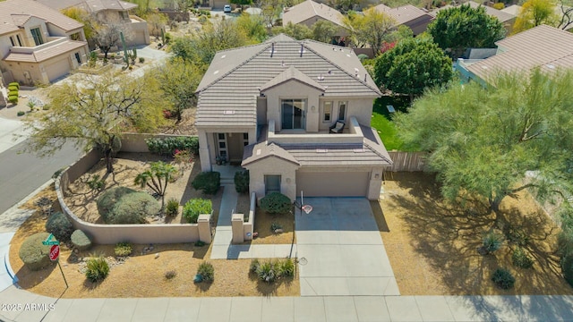 view of front of house with a garage, a tile roof, fence, concrete driveway, and stucco siding