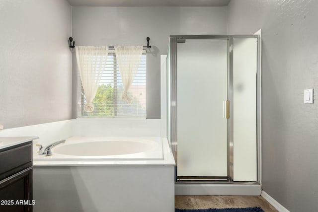 full bathroom featuring a stall shower, a garden tub, a textured wall, and vanity