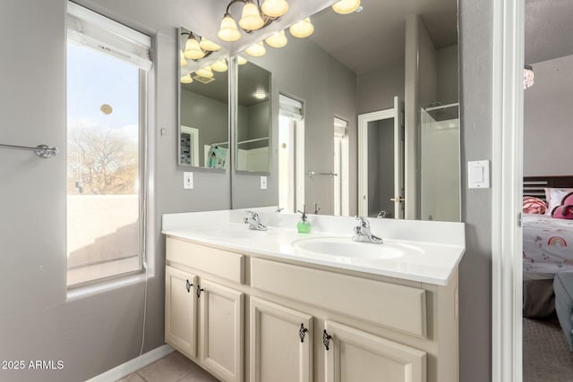 ensuite bathroom featuring double vanity, tile patterned flooring, a sink, and connected bathroom