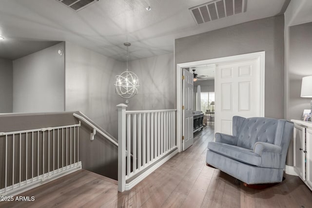 interior space with wood-type flooring, visible vents, and an upstairs landing