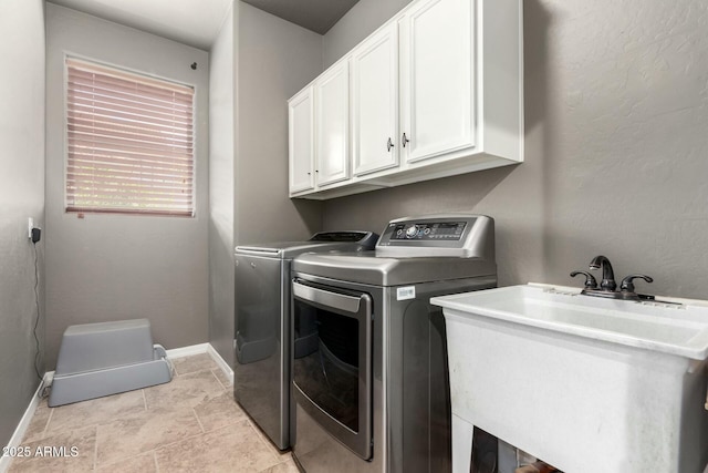 washroom with cabinet space, baseboards, separate washer and dryer, and a sink