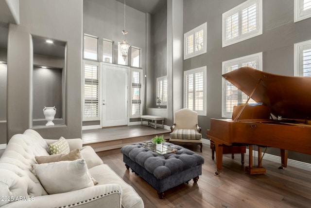 living room with hardwood / wood-style flooring, a high ceiling, and baseboards