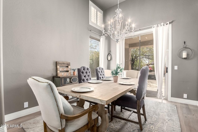 dining space featuring light wood-style floors, baseboards, and a chandelier