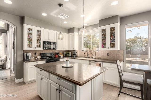 kitchen with visible vents, white cabinets, a sink, black appliances, and backsplash