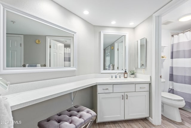 bathroom featuring hardwood / wood-style floors, vanity, toilet, and walk in shower