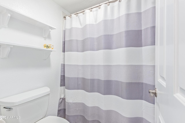 bathroom featuring a shower with curtain and toilet