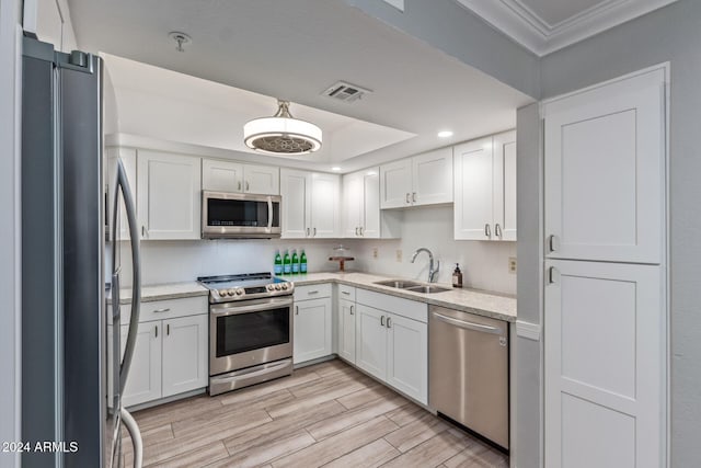 kitchen with white cabinets, stainless steel appliances, light stone countertops, and sink