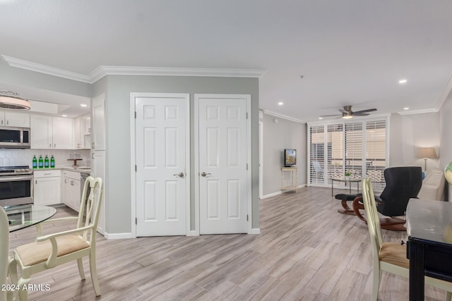 kitchen with light wood-type flooring, backsplash, stainless steel appliances, ceiling fan, and white cabinetry