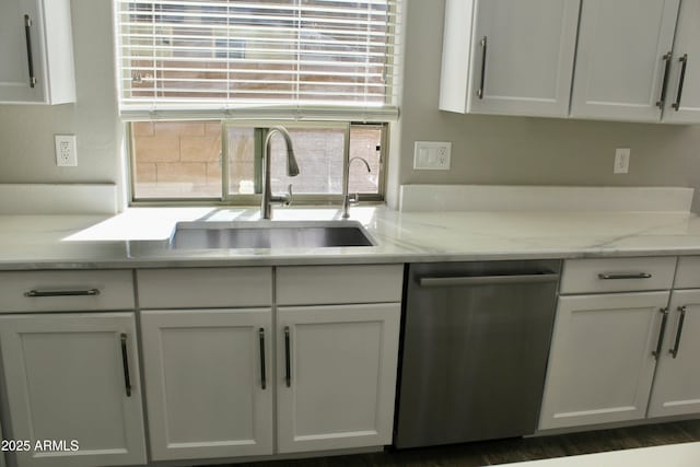 kitchen with stainless steel dishwasher, light stone counters, white cabinets, and sink