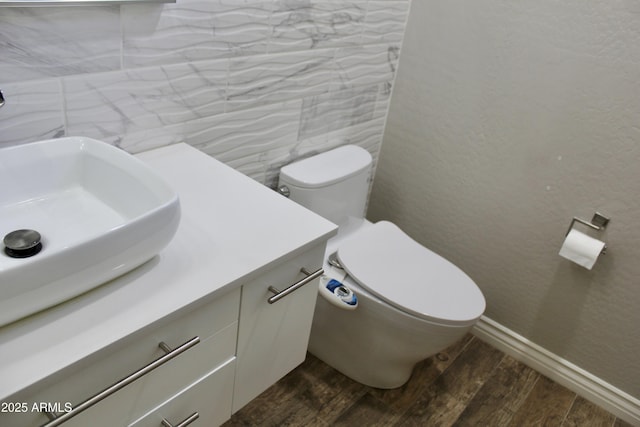 bathroom featuring vanity, wood-type flooring, tile walls, and toilet