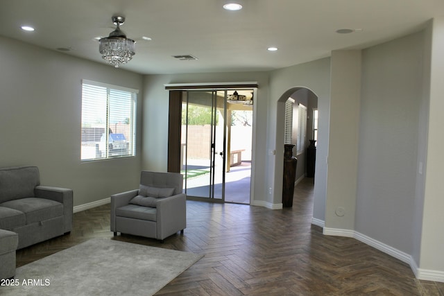 living room featuring dark parquet flooring and a chandelier