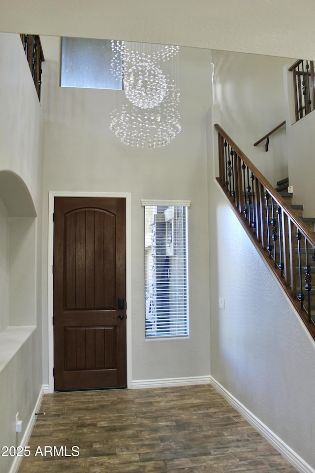 foyer featuring a towering ceiling, hardwood / wood-style flooring, and a notable chandelier