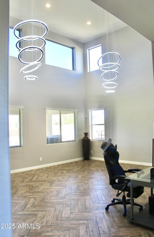 office featuring a towering ceiling, parquet floors, and a notable chandelier