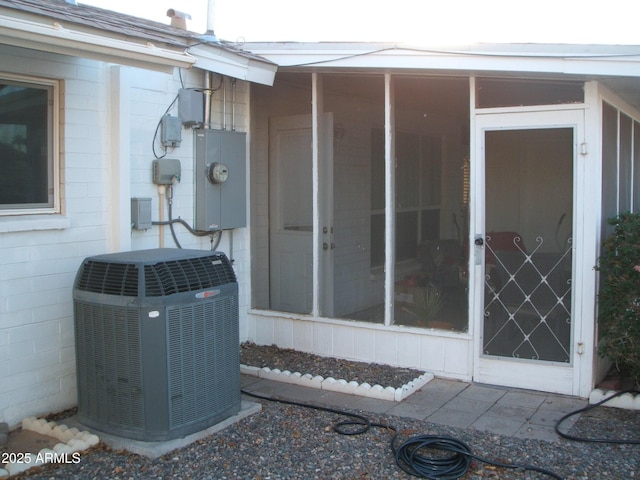 exterior details with electric meter, concrete block siding, and central AC unit