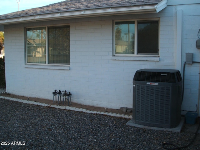 view of property exterior with central AC unit and a shingled roof