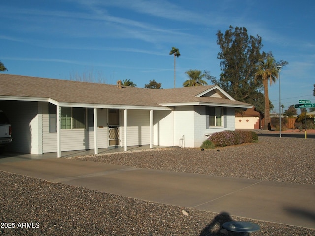 ranch-style house with driveway and roof with shingles