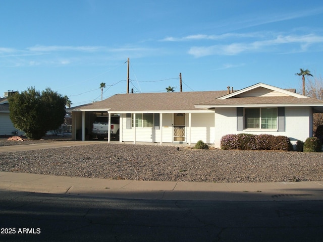 ranch-style home with an attached carport, roof with shingles, and driveway