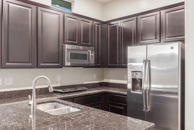 kitchen featuring dark stone countertops, sink, dark brown cabinets, and appliances with stainless steel finishes