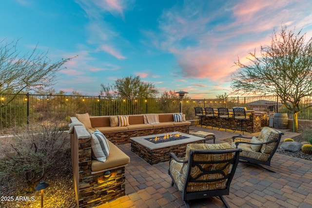 patio terrace at dusk with an outdoor living space with a fire pit and an outdoor bar