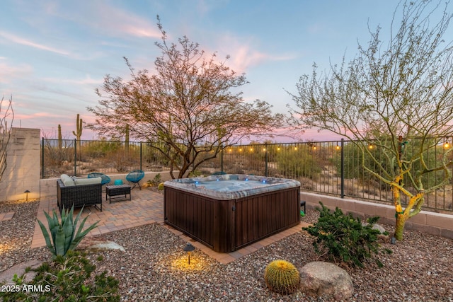 yard at dusk with a hot tub, outdoor lounge area, and a patio area