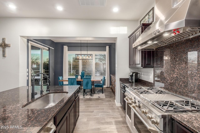 kitchen featuring dark brown cabinetry, extractor fan, sink, and range with two ovens