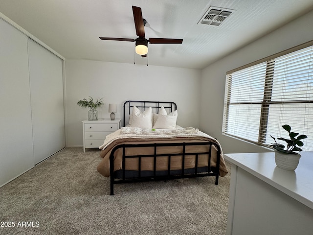 carpeted bedroom with ceiling fan and a closet