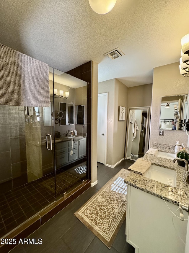 bathroom featuring vanity, a textured ceiling, and a shower with shower door