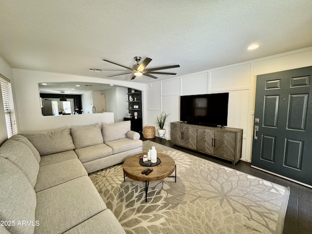 living room with wood-type flooring, ceiling fan, and a textured ceiling