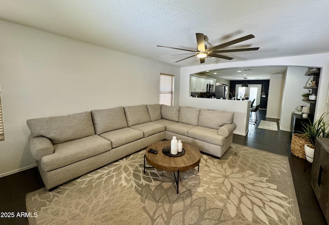 living room featuring ceiling fan, hardwood / wood-style flooring, and a textured ceiling