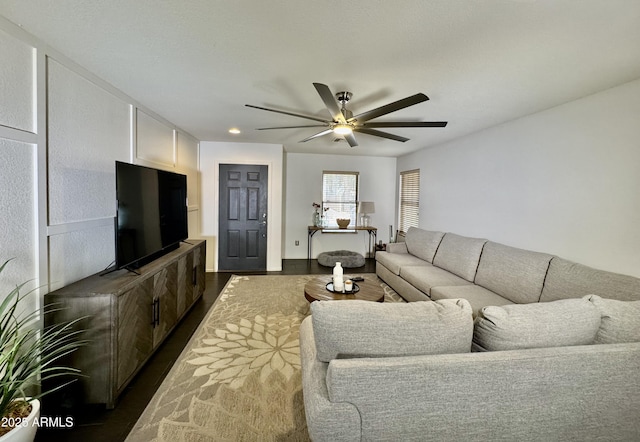 living room featuring dark wood-type flooring and ceiling fan