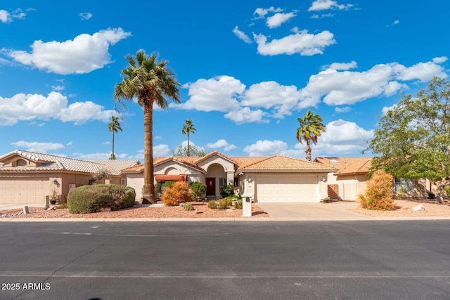 view of front of home featuring fence, a tile roof, stucco siding, a garage, and driveway